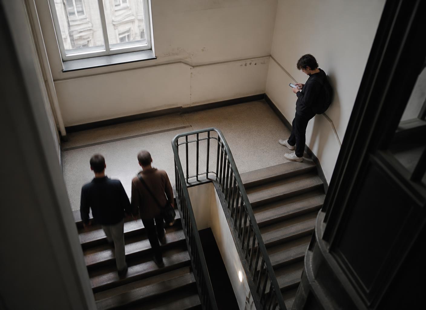 People moving up and down a concrete stairwell, seen from above