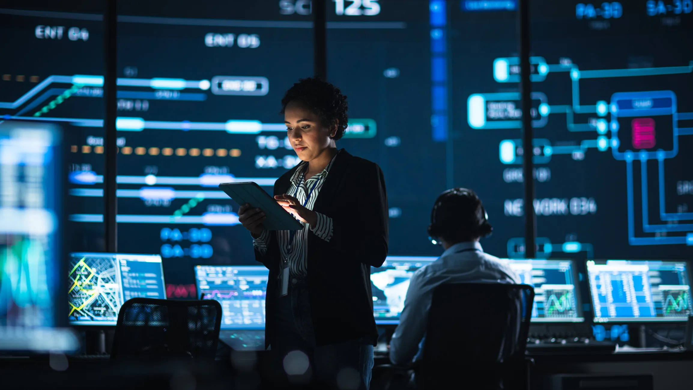 A woman using a tablet in a high-tech control room, a scene from the discussion of AI action plans.