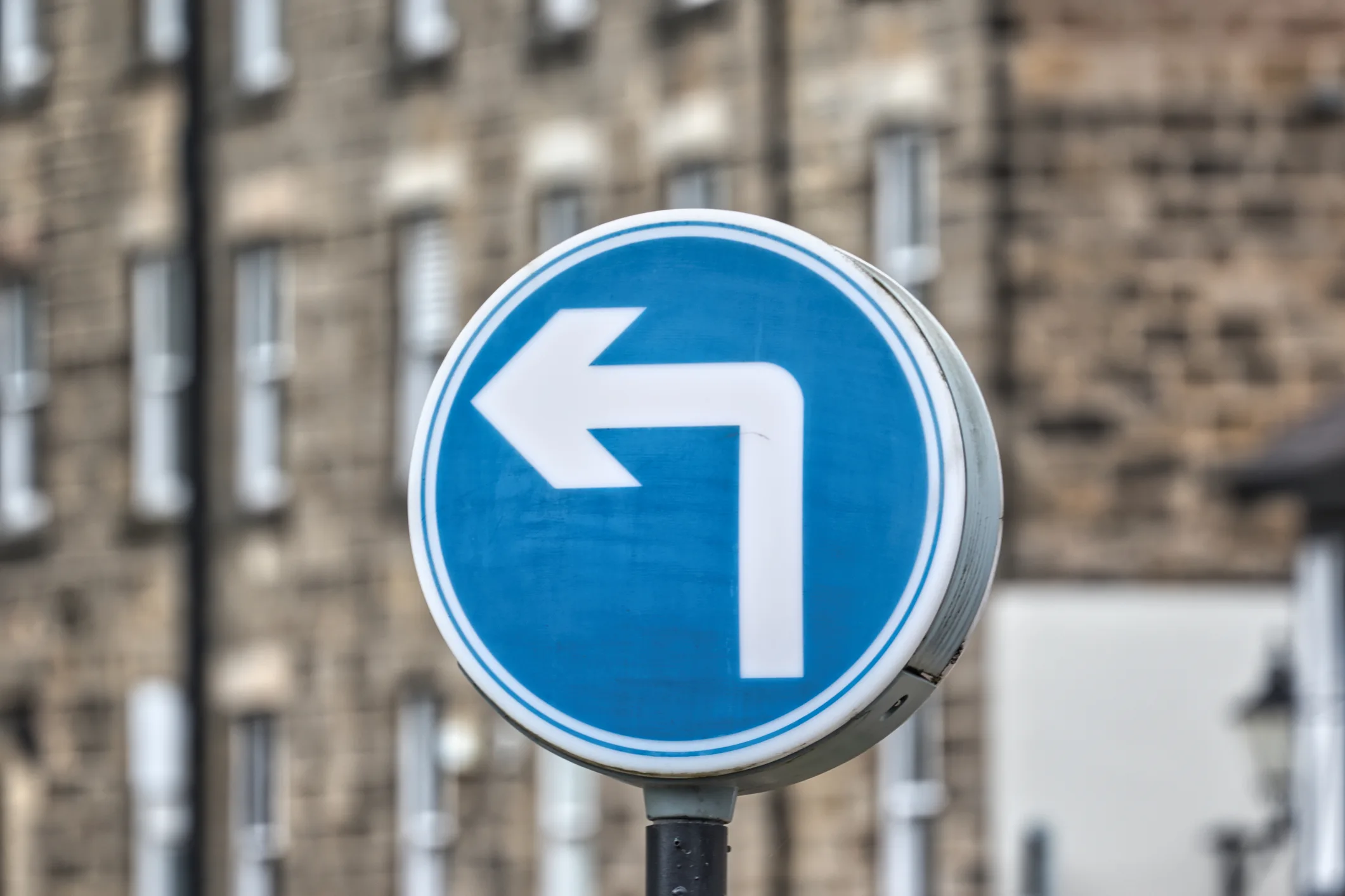 A blue and white mandatory left turn road sign, used as a visual metaphor for a political shift.
