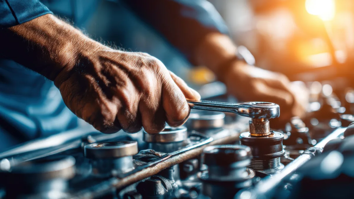 Mechanic using a wrench to adjust engine parts on an extended workbench