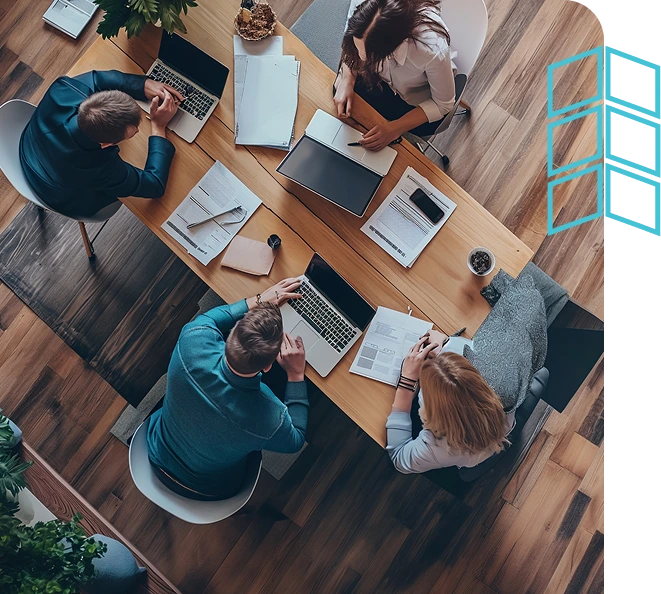Team meeting from above, focused on laptops and documents, representing strategies to outthink disruption.