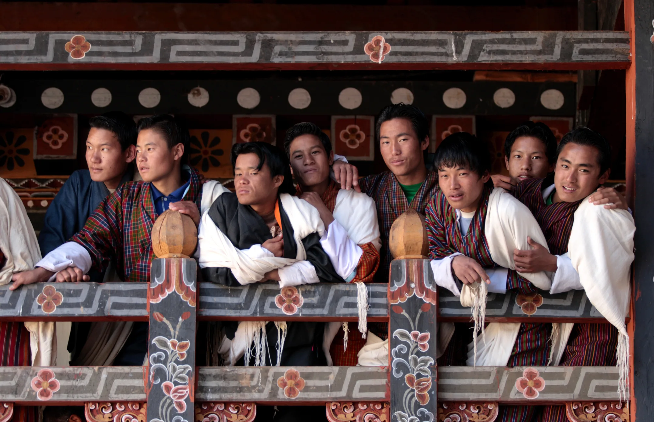 Young men in Bhutan wearing traditional attire, symbolizing Gross National Happiness as an alternative to GDP-focused measures of national success.