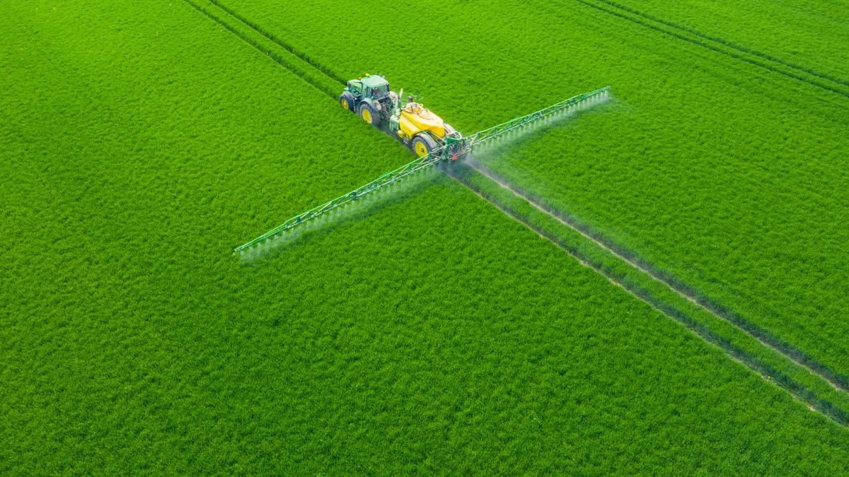 A modern tractor spraying crops in a lush green field in Poland, showcasing precision agriculture and climate-smart farming practices.