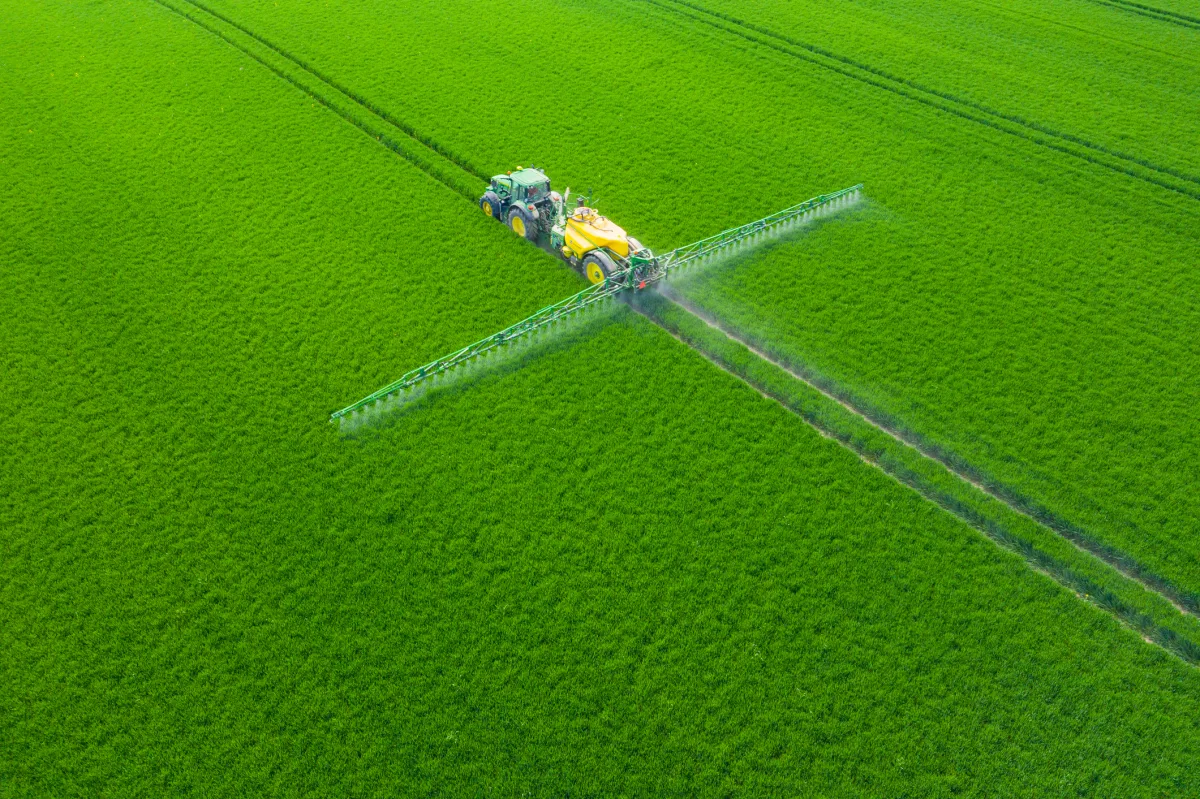 A modern tractor spraying crops in a lush green field in Poland, showcasing precision agriculture and climate-smart farming practices.