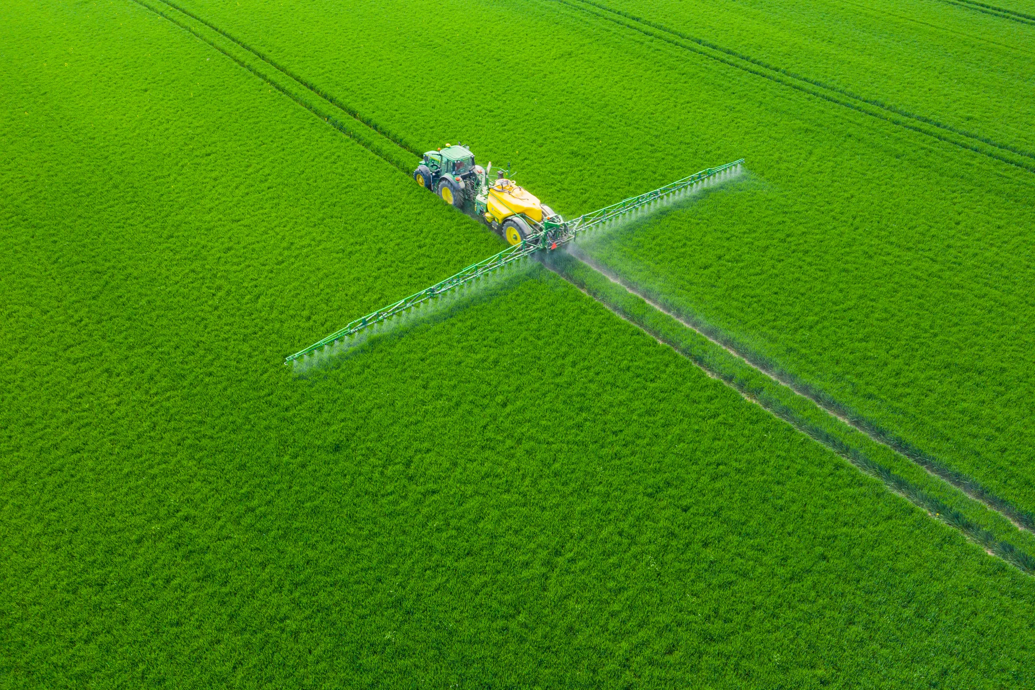 A modern tractor spraying crops in a lush green field in Poland, showcasing precision agriculture and climate-smart farming practices.