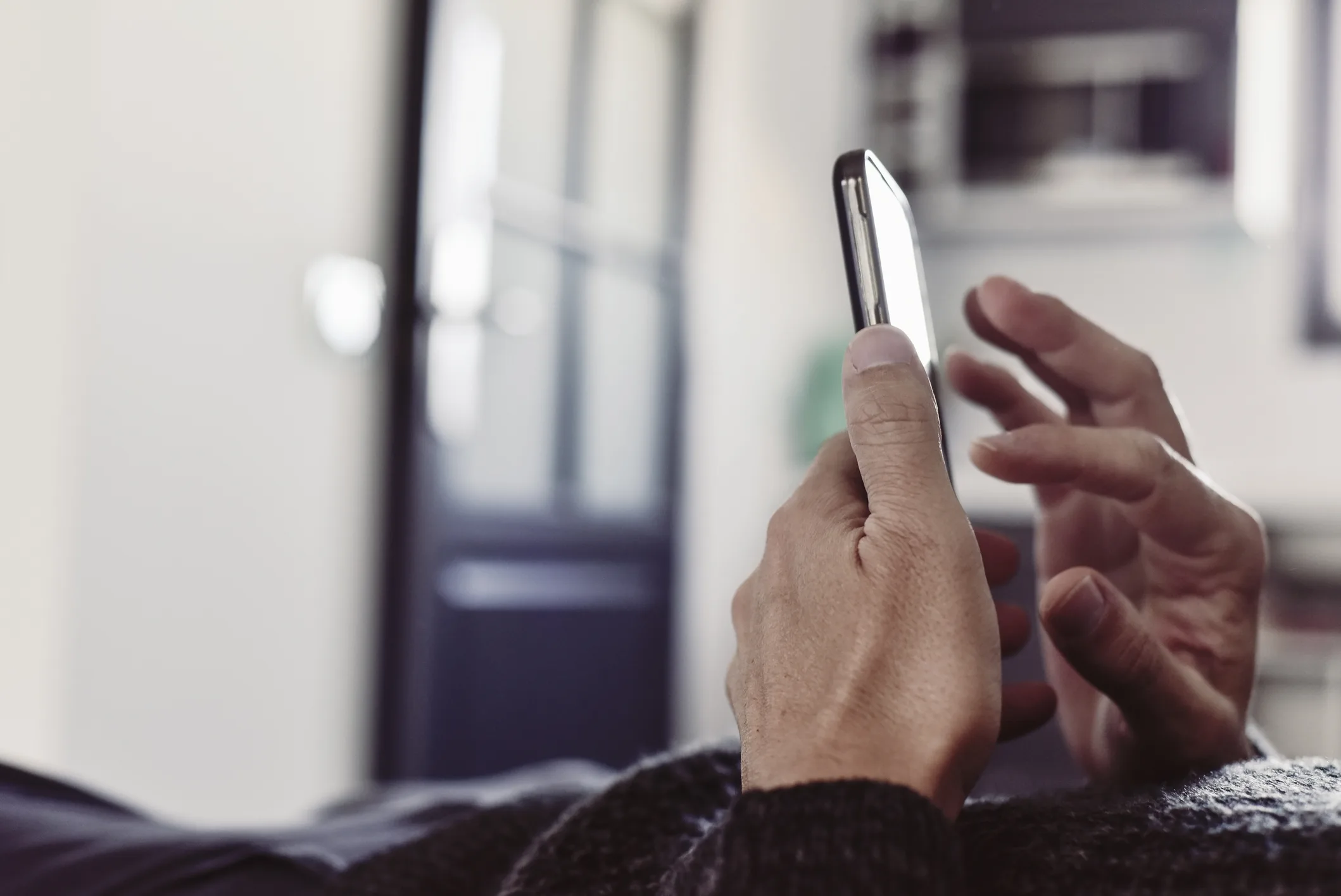 Close-up of a person using a smartphone, symbolizing dating apps and the monetisation of loneliness in the global isolation economy.