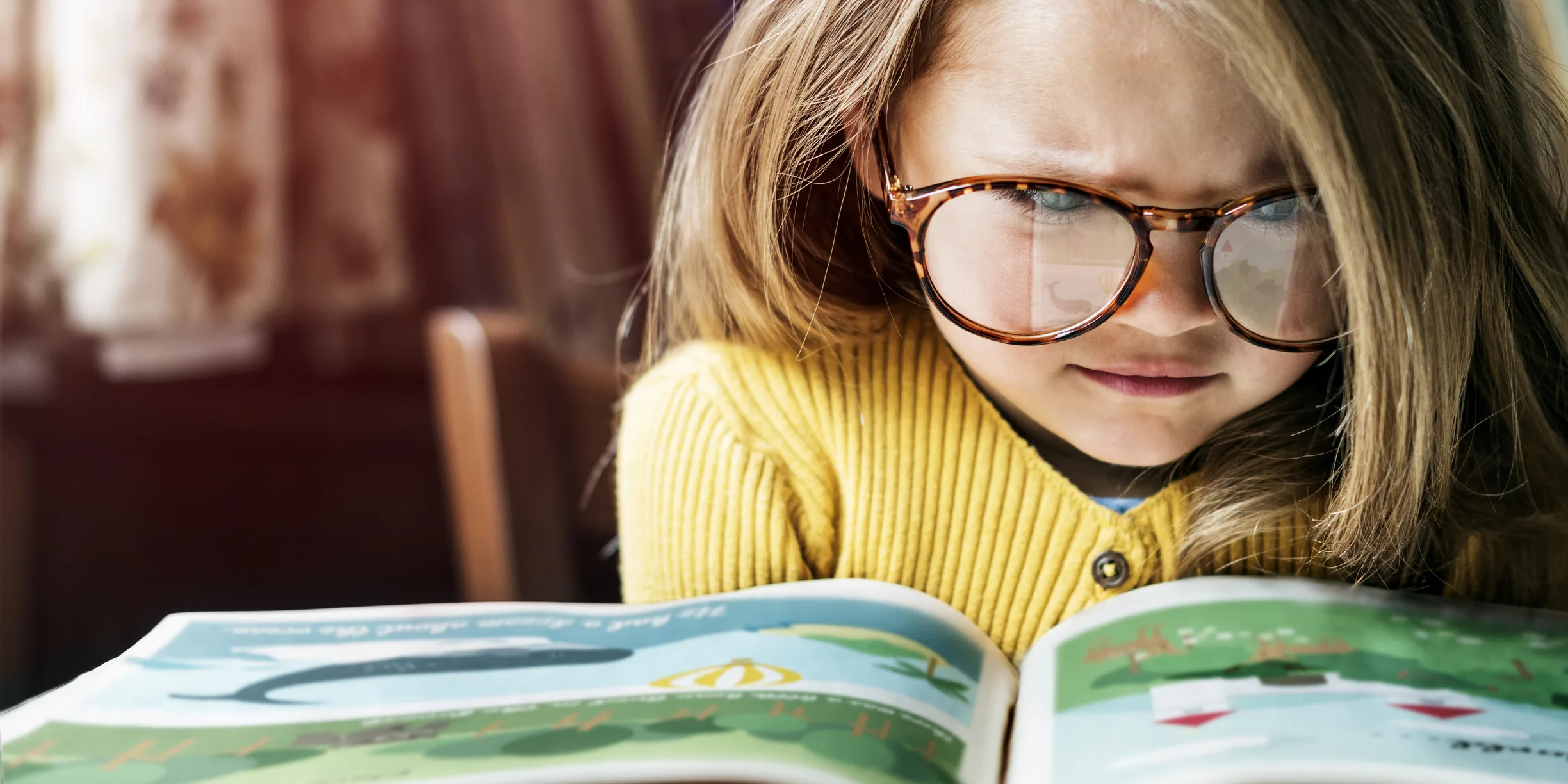 Little girl with oversized glasses struggling to read a picture book, symbolising the challenges of miscommunication and messy storytelling in business reinvention.