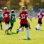 Generation Alpha children playing football outdoors, showing a move from digital screens to physical activity and sport.