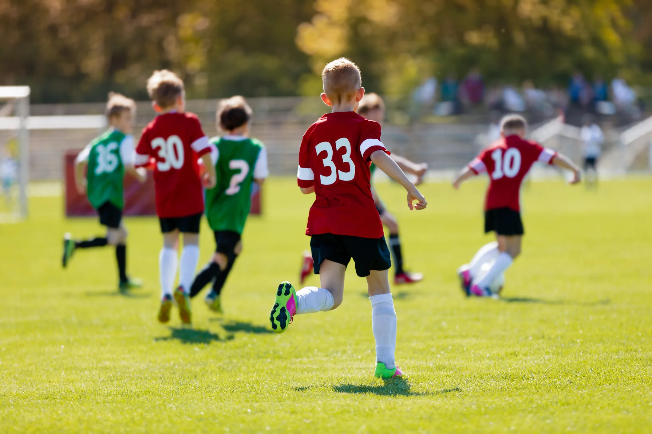 Generation Alpha children playing football outdoors, showing a move from digital screens to physical activity and sport.