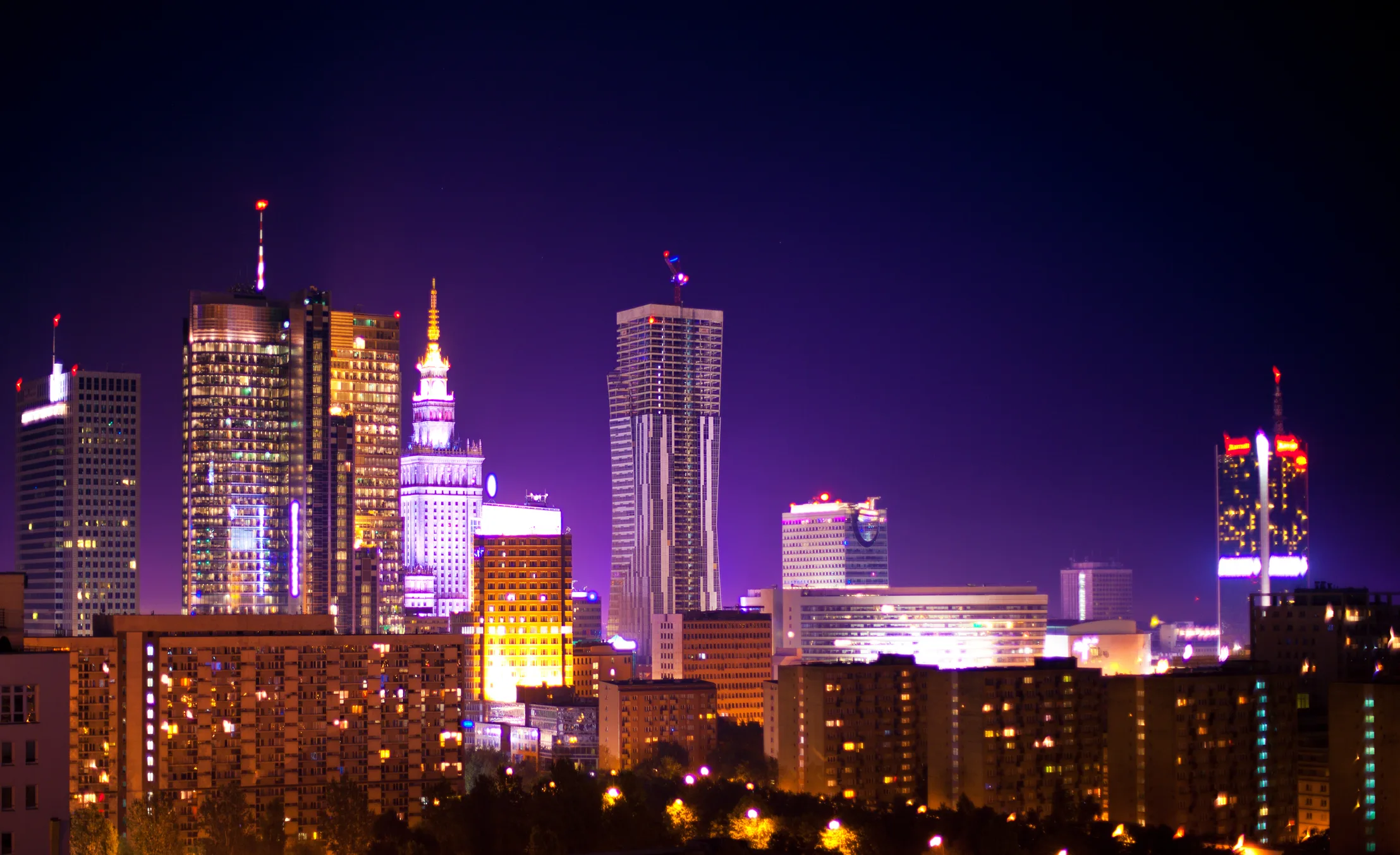 Night view of Warsaw skyline with modern skyscrapers, symbolizing Poland’s economic rise to the trillion-dollar GDP milestone.