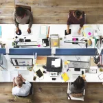 Employees working at open-plan office desks, symbolizing corporate mandates forcing staff back instead of remote work freedom.