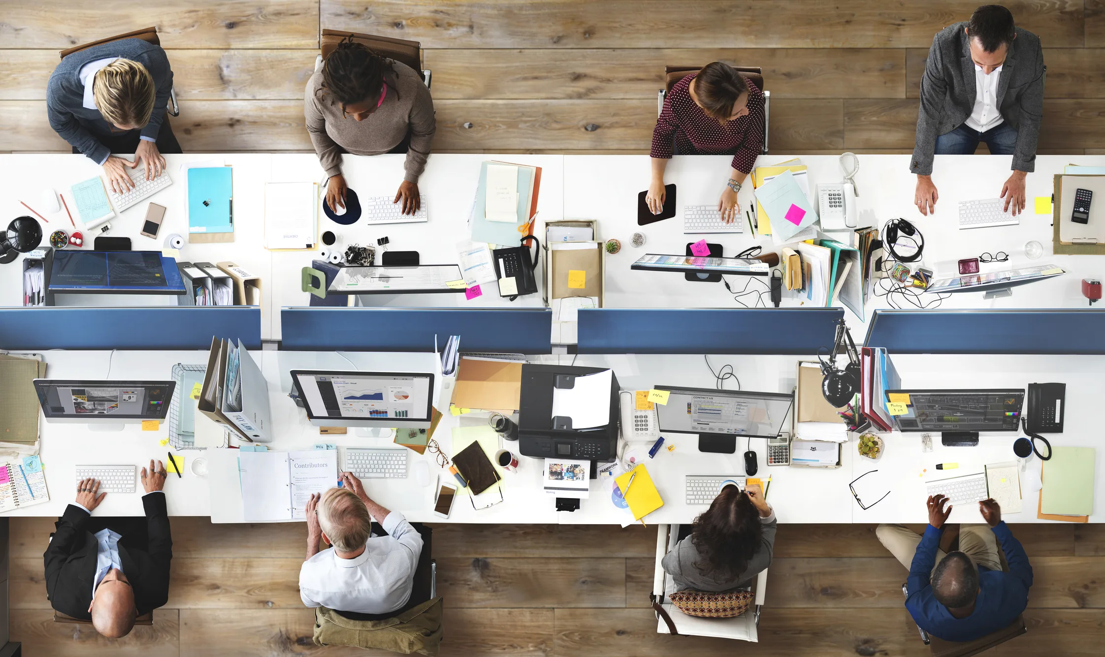 Employees working at open-plan office desks, symbolizing corporate mandates forcing staff back instead of remote work freedom.