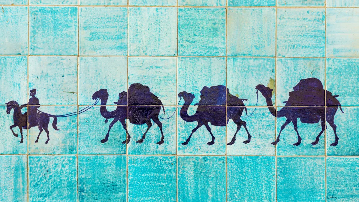 Silhouette of a camel caravan with a rider on blue tiles, symbolizing Uzbekistan’s trade routes, cultural heritage, and connection to the EU