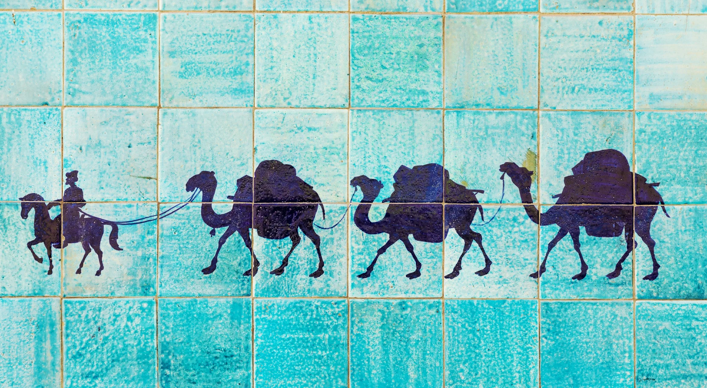 Silhouette of a camel caravan with a rider on blue tiles, symbolizing Uzbekistan’s trade routes, cultural heritage, and connection to the EU