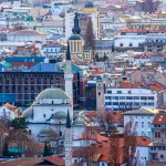 A panoramic view of Sarajevo’s historic skyline with Ottoman-era mosques, Austro-Hungarian buildings, and modern architecture.