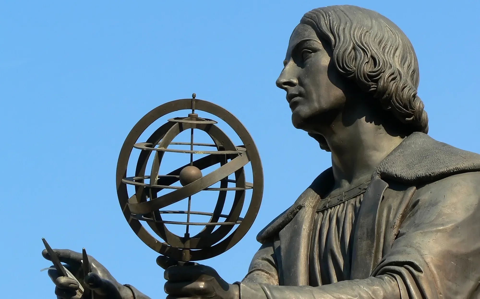 Statue of Nicolaus Copernicus holding an armillary sphere against a blue sky, symbolizing science, discovery, and Central Europe’s spirit of reinvention.